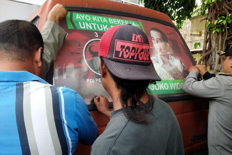 Stiker pada angkutan umum yang menampilkan gambar Calon Presiden dan partai pengusung dilepas saat Bawaslu Jombang dan aparat gabungan menggelar razia, Selasa (27/11/2018).