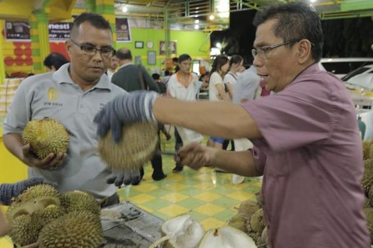 Zainal Abidin (baju merah) alias Ucok pemilik usaha Durian Ucok di Kota Medan, Sumatera Utara, sedang memilihkan durian pesanan pelanggan, Kamis (25/8/2016)