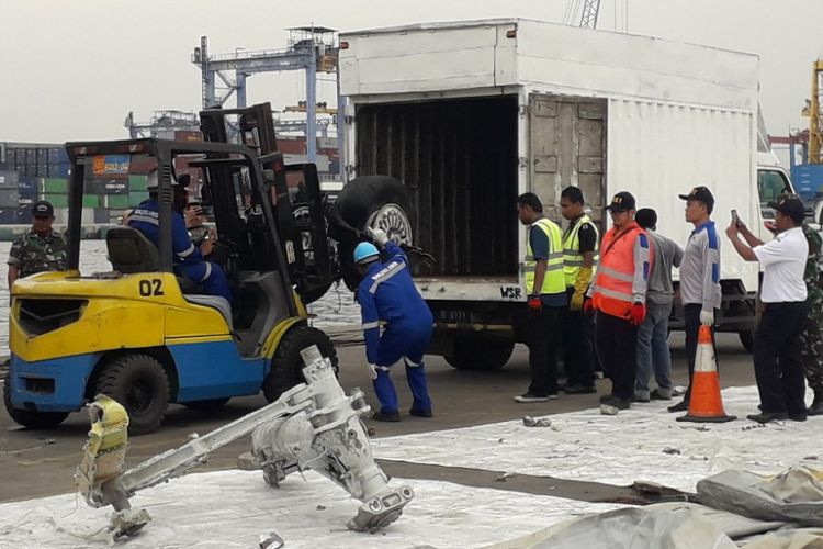 Petugas memasukkan roda pesawat Lion Air PK-LQP ke dalam mobil sebelum dibawa pergi dari Dermaga JICT 2 Pelabuhan Tanjung Priok, Senin (5/11/2018). 