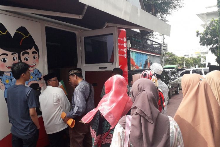 Pemohon pembuatan paspor mengantre di depan mobil layanan paspor yang terparkir di Kantor Imigrasi Kelas I Khusus Jakarta Barat, Sabtu (2/2/2019).