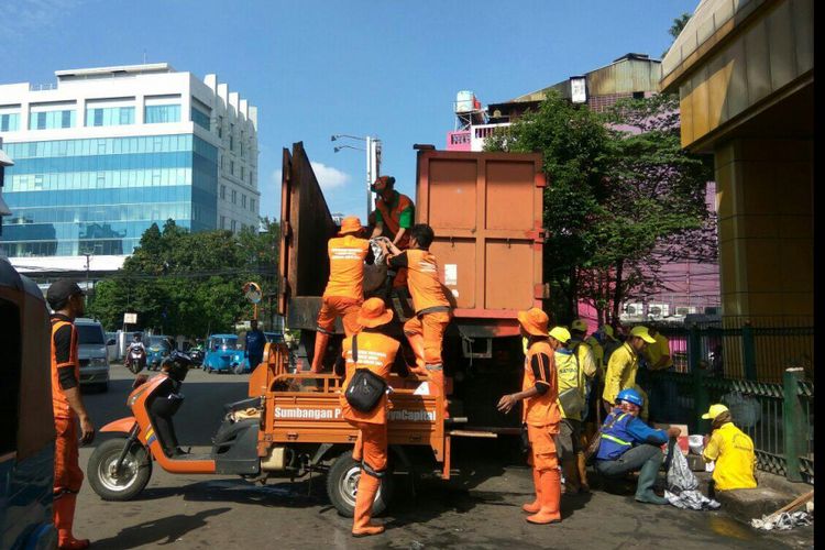Petugas Prasarana dan Sarana Umum (PPSU) bahu membahu membersihkan sampah dan mengangkutnya ke truk di Jalan Kebon Sirih, Minggu (25/2/2018).