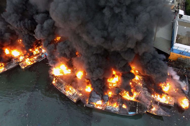 Asap tebal mengepul dari kapal-kapal yang terbakar di Pelabuhan Muara Baru, Jakarta Utara, Sabtu (23/2/2019). Hingga pukul 18.30 api masih terlihat membakar beberapa kapal, meski begitu proses pemadaman masih di lakukan,  di tengah angin yang kencang.