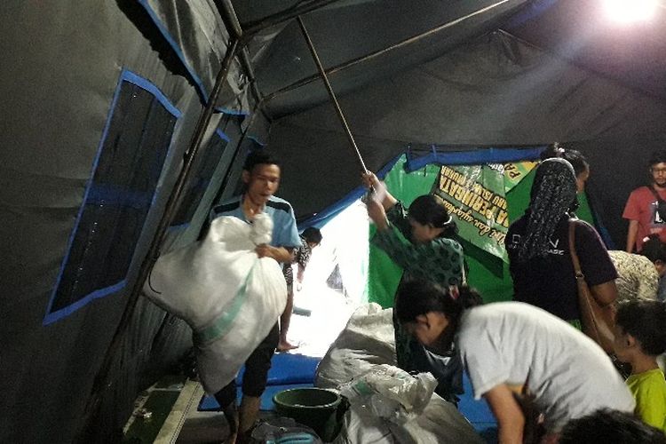 Sejumlah warga pengungsian korban kebakaran di Jalan Tomang Raya, Grogol Petamburan, Jakarta Barat membersihkan air hujan yang masuk ke tenda dan merapikan tumbukan barang milik mereka pada Selasa (22/1/2019).