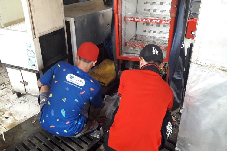 Dua orang karyawan warung milik Rajab membereskan sisa-sisa pecahan kaca dari lemari es yamg rusak akibat kerusuhan pada Rabu (22/5/2019) kemarin