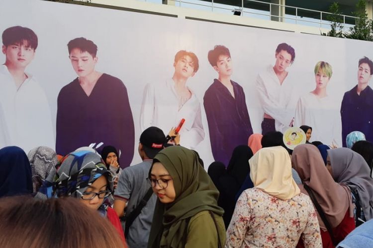 Para fans boyband iKON berkerumun di depan billboard bergambar sang idola di area Tennis Indoor Senayan, Jakarta, Minggu (18/11/2018).