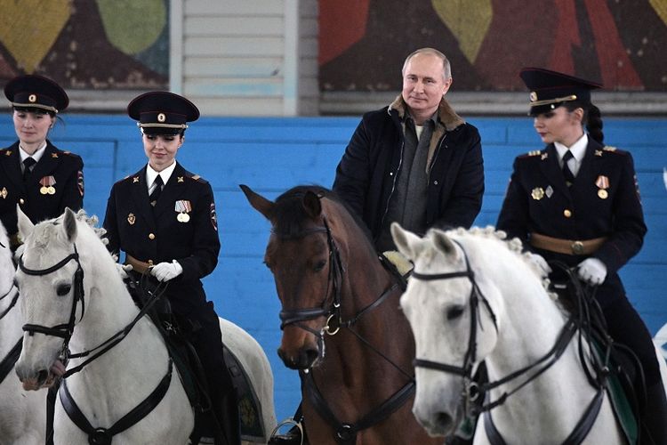 Presiden Rusia Vladimir Putin menunggangi kuda bersama petugas polisi wanita saat peringatan Hari Perempuan Internasional di Moskwa, Kamis (7/3/2019).