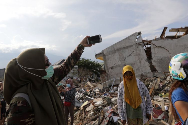 Orang mengambil selfie di lokasi reruntuhan gedung akibat gempa di Palu, Sulawesi Tengah bulan Oktober lalu.