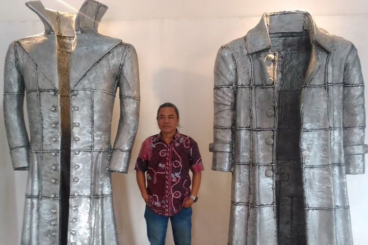 Timbul Raharjo (47), perupa asal DI Yogyakarta bersama dua jubah logam yang merupakan hasil karya terbarunya pada tahun ini di Jogja Galeri, Jalan Pekapalan, Alun-alun Utara, Yogyarkata, Selasa (11/7/2017).