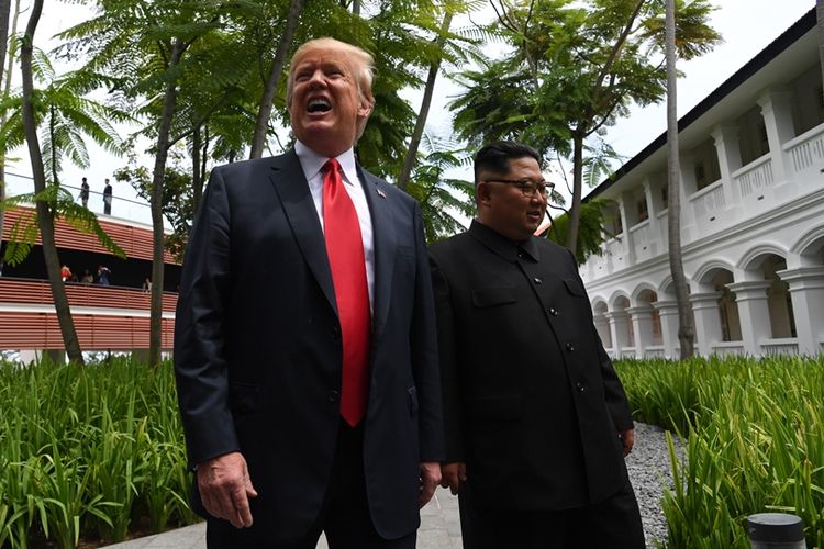Presiden AS Donald Trump (kiri) berjalan bersama Pemimpin Korea Utara Kim Jong Un menuju lokasi penandatanganan dokumen usai makan siang bersama.