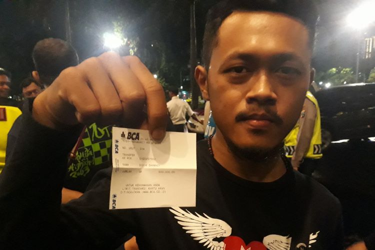 Salah seorang penonton menunjukkan bukti transfer pembelian tiket konser Dewa 19 di Grand City Surabaya, Minggu (10/3/2019)