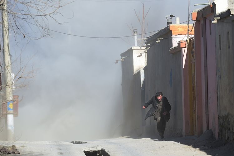 Seorang pria Afghanistan melarikan diri setelah ledakan ketiga di sebuah pusat kebudayaan Syiah di Kabul, Afganistan, Kamis (29/12/2017). (AFP/Shah Marai)