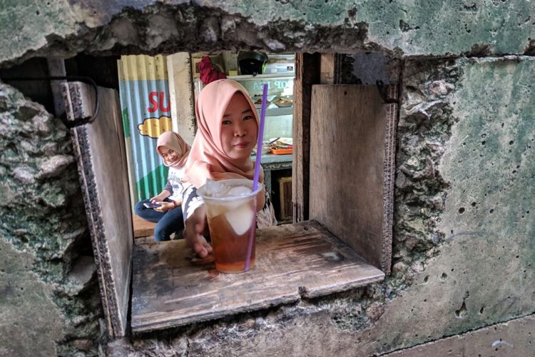Salah seorang anak perempuan Damiah menyajikan pesanan pembeli di warung lubang yang berada di Grand Lucky SCBD, Senayan, Jakarta Selatan