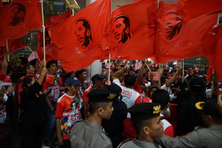 Kelompok relawan Projo turut memberikan dukungan kepada pasangan capres-cawapres nomor urut 01 Joko Widodo-Maruf Amin saat debat pertama Pilpres di Hotel Bidakara, Jakarta Selatan, Kamis (17/1/2019) malam.  Mereka memadati bahu jalan yang menuju lobbby Hotel Bidakara. Ratusan pendukung itu membawa bendera berwarna merah dan bergambar wajah Jokowi.
