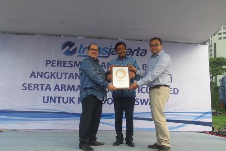 Direktur Institute for Transportation and Development Policy Indonesia, Yoga Adiwinarto (kanan) saat menyerahkan sertifikat bronze standard bus rapid transit (BRT) kepada Direktur Utama PT Transportasi Jakarta Antonius Kosasih (kiri) di Lapangan Parkir Timur, Senayan, Selasa (22/12/2015). Turut menyaksikan Wakil Gubernur Djarot Saiful Hidayat (tengah). Sertifikat diberikan untuk penilaian ITDP yang menganggap ada enam koridor layanan bus transjakarta sudah berstandar sistem BRT internasional.