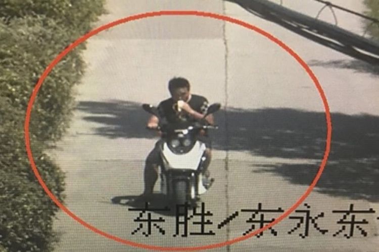 Foto rekaman kamera pengawas yang menunjukkan seorang pria tengah memakan pisang sambil mengendarai motor listrik di Shanghai.