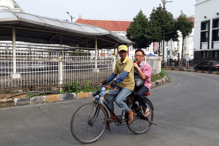 Seorang pengojek sepeda ontel membonceng penumpang di kawasan Kota Tua, Jakarta Barat, Senin (28/5/2018).