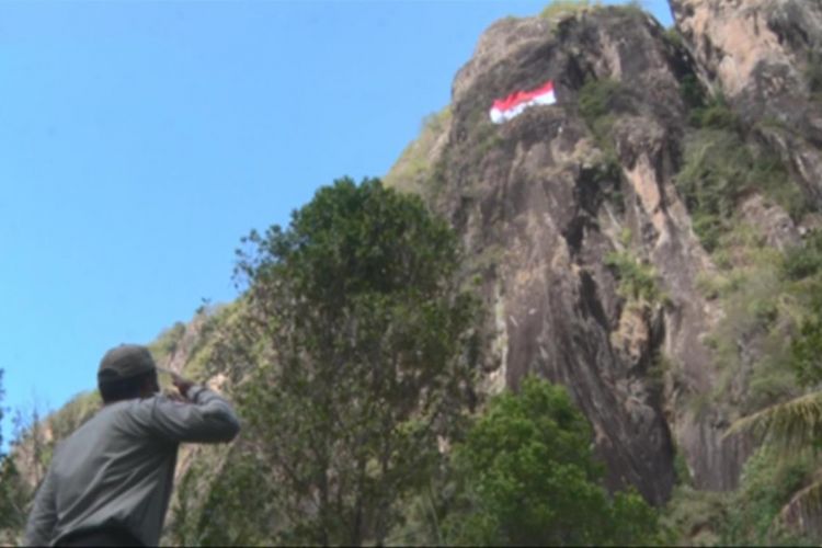 Pemimpin upacara hormat kepada bendera yang berkibar di tebing Gunung Sepikul, Kabupaten Trenggalek, Jawa Timur (15/8/2018).