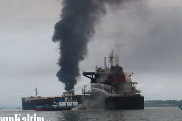 Sebuah kapal memadamkan api yang membakar sebuah kapal kargo pengangkut batu bara di teluk Balikpapan, Sabtu (31/3/2018). 