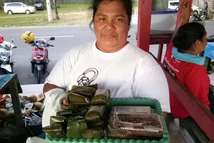 Dina Suitela (41), menawarkan hidangan rwbia racikannya dengan kue talam sebagai pendampingnya, di Pantai Natsepa, Minggu (12/11/2017). Rwbia ialah kerang atau bia yang diolah dengan racikan rempah khas Maluku.