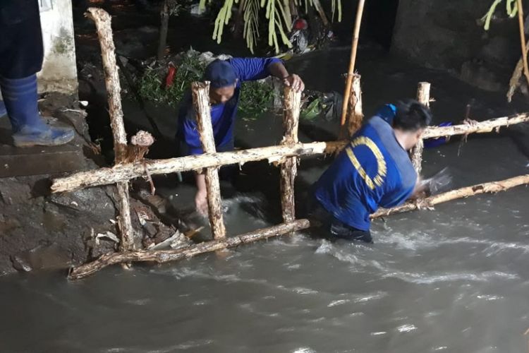 Pasukan biru Dinas Sumber Daya Air menangani tanggul jebol di Jatipadang, Pasar Minggu, Jakarta Selatan, Minggu (14/1/2019).