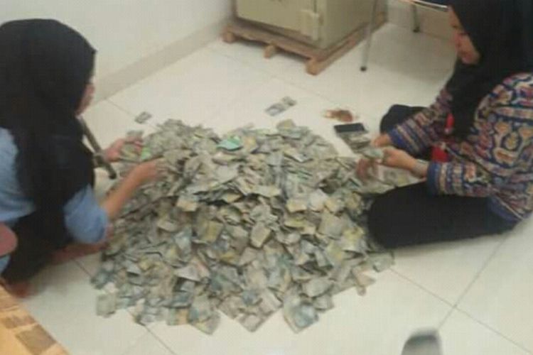 Dua karyawan salah satu dealer penjualan sepeda motor di Kabupaten Bone, Sulawesi Selatan tengah menghitung sekarung uang dalam pecahan dua ribu rupiah yang dibawah oleh salah seorang warga untuk membeli motor. Kamis, (27/12/2018).