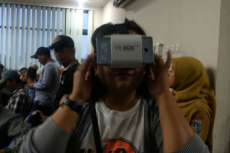 Seorang warga Kelurahan Srengseng, Rihla saat mencoba kacamata virtual reality, Senin (16/10/2017).