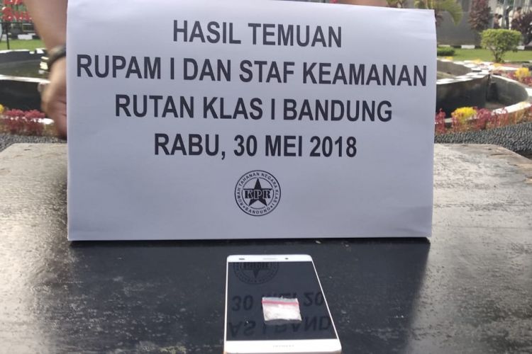 Tampak barang bukti satu unit ponsel dan sabu tengah diperlihatkan seorang petugas. Barang haram tersebut ditemukan dari seorang napi di Rutan Kebonwaru, Bandung.