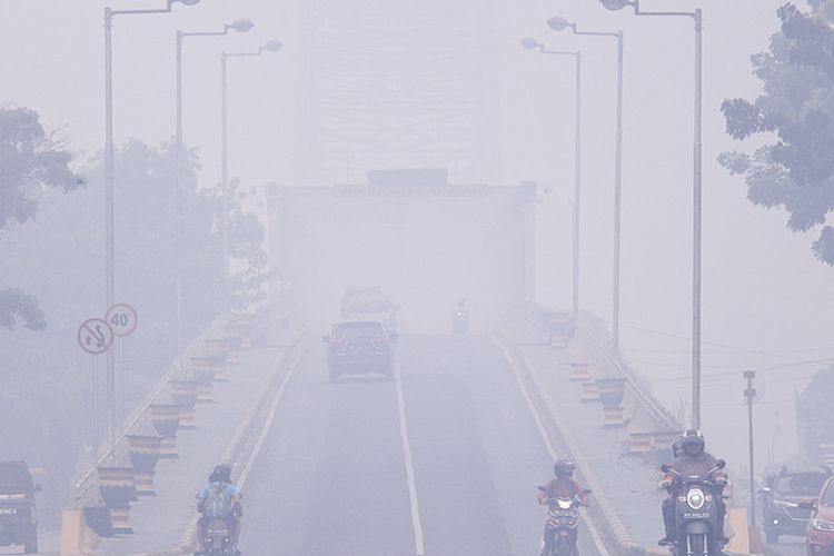 Pengendara melintas di Jembatan Kahayan yang diselimuti kabut asap di Palangkaraya, Kalimantan Tengah, Minggu (15/9/2019). Kota Palangkaraya kembali diselimuti kabut asap pekat akibat kebakaran hutan dan lahan di sejumlah daerah di Kalimantan Tengah sehingga menimbulkan aroma yang menyengat dan menggangu aktivitas warga.