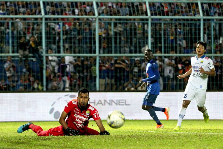 Penjaga kiper Persib Bandung, M Aqil Savik menghalau bola pemain Arema FC saat laga tunda Pekan 4 Liga 1 2019 yang berakhir dengan skor 5-1 di Stadion Kanjuruhan Kabupaten Malang, Jawa Timur (30/07/2019) malam.