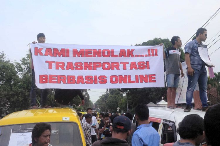 Sopir angkot membentangkan spanduk penolak angkutan online saat demonstrasi di Balai Kota Sukabumi, Jawa Barat, Selasa (26/9/2017).