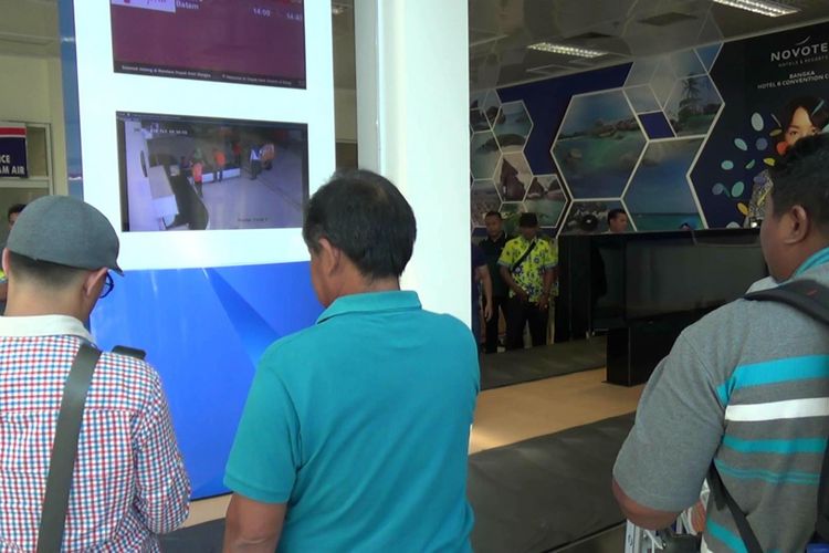 Penumpang menyaksikan proses pembersihan dan bongkar muat barang dari monitor di ruang bagasi bandara Depati Amir Pangkal Pinang.