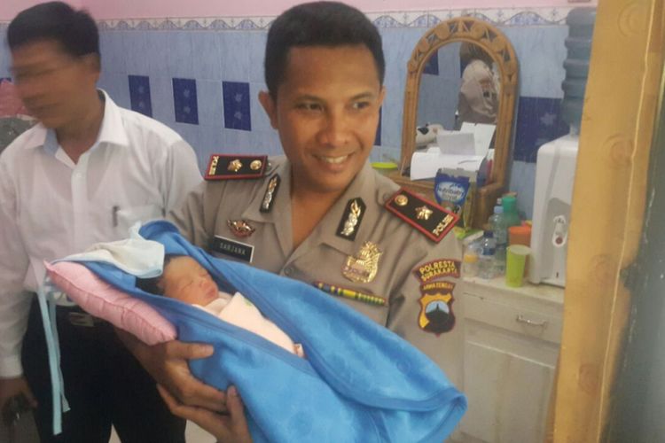 Kapolsek Banjarsari Kompol I Komang menggendong bayi laki-laki di halaman belakang Puskesmas Krembyongan, Sekomulyo, Kelurahan Kadipiro, Kecamatan Banjarsari, Solo, Jawa Tengah, Senin (5/3/2018).