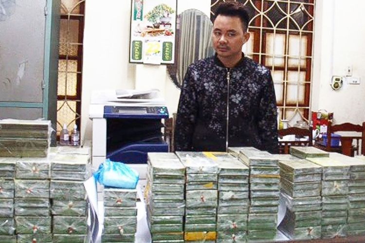 Foto yang dirilis media Vietnam, menunjukkan tersangka pemimpin kelompok penyelundupan narkoba, Tran Van Bang (31), berdiri di belakang tumpukan paket heroin yang disita polisi Vietnam di provinsi Cao Bang.