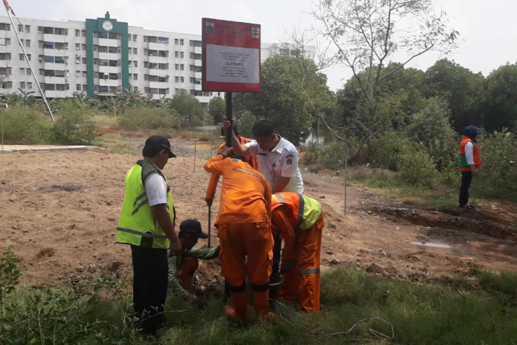 Petugas Dinas LH memasang papan peringatan di area temuan gundukan tanah yang diduga limbah B3 di kawasan Marunda, Jakarta Utara, Rabu (9/1/2019).