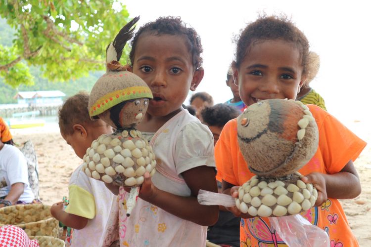 Anak Papua sedang memegang boneka buatan Komunitas Mamak Noken, di pulau Sauwandarek Raja Ampat.