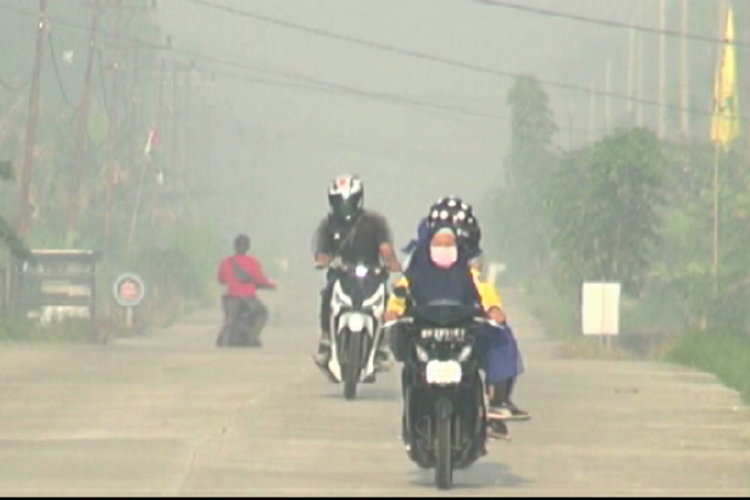 Kabut asap tebal menyelimuti wilayah Kecamatan Rupat, Kabupaten Bengkalis, Riau, Kamis (21/2/2019). Salah seorang pengendara sepeda motor terlihat mengenakan masker saat melintas di jalan.