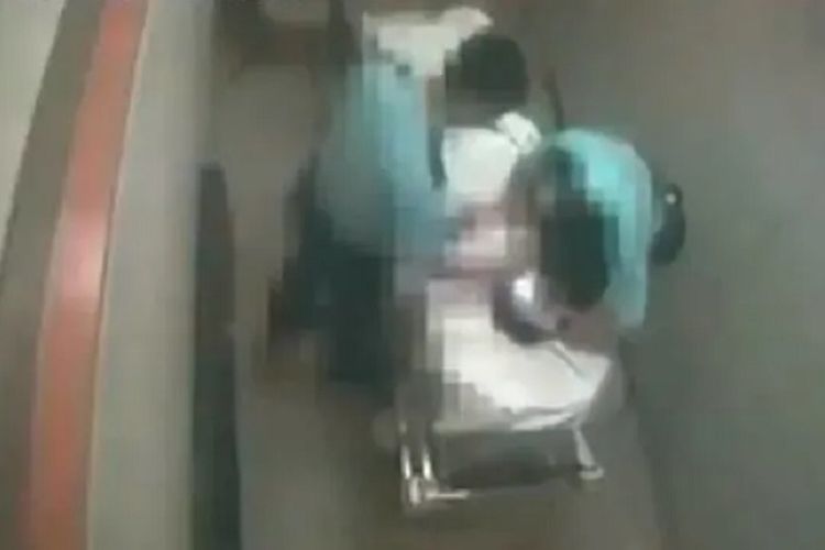 Tangkapan layar rekaman CCTV rumah sakit yang menunjukkan dua oknum polisi melakukan pemukulan terhadap seorang pria di atas brankar.