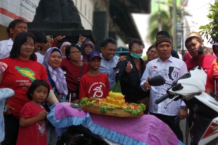 Para penyandang disabilitas menggelar tumpengan nasi kuning untuk merayakan kemenangan Jokowi-Maruf Amin versi quick count di bawah patung difabel depan Pasar Kleco, Solo, Jawa Tengah, Minggu (21/4/2019).