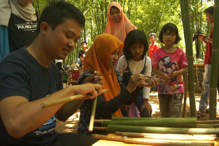 Pengunjung dewasa Taman Wisata Kampung Bambu menikmati permainan tembak bambu yang dijual warga setempat.