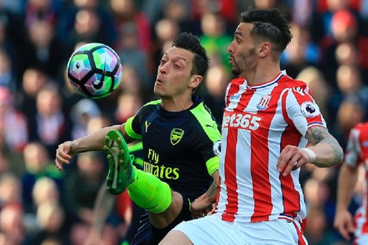 Mesut Oezil dan Geoff Cameron berebut bola dalam pertandingan Premier League antara Arsenal dan Stoke City di Britannia, Sabtu (13/5/2017). 