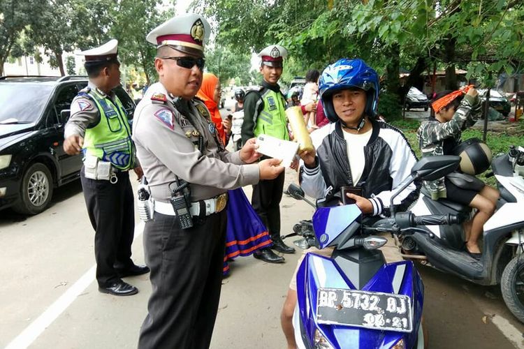 Salah seorang petugas Satlantas Polresta Barelang memberikan handuk kecil kepada pengendara sepeda motor yang taat aturan dalam operasi Zebra Siligi hari keenam di Batam
