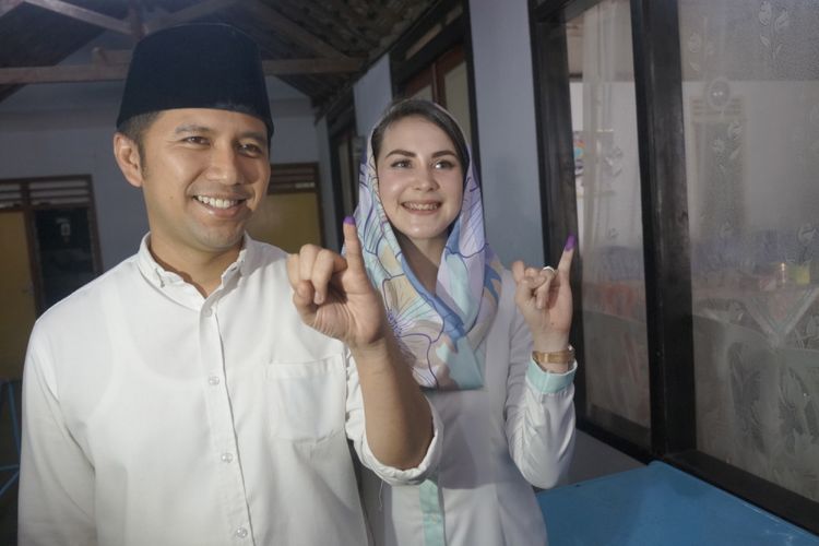 Cawagub Jatim Emil Elestianto Dardak (kiri) didampingi istri, Arumi Bachsin, menunjukkan bekas tinta pada ujung jari kelingking tanda telah menyalurkan hak pilih (mencoblos) di TPS 05 Kelurahan Ngantru, Trenggalek, Jawa Timur, Rabu (27/6/2018). Emil yang maju bursa Pilkada Jatim mendampingi Cagub Khofifah Indar Parawansa mengawali rangkaian penggunaan hak pilihnya dengan sungkem ke orang tua dan ziarah makam leluhur sebelum mencoblos di TPS 05 Kelurahan Ngantru, Trenggalek.