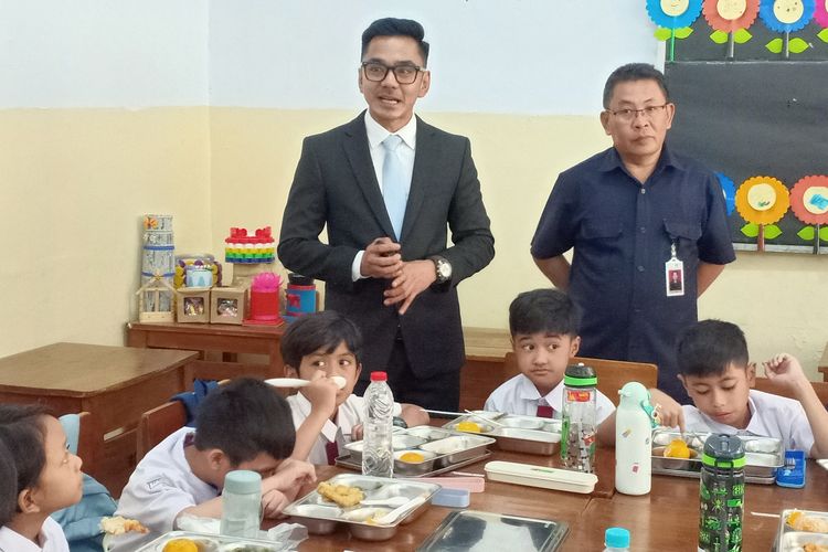 Juru Bicara Kantor Komunikasi Kepresidenan Dedek Prayudi (kiri) dan  Kepala Sekolah Dasar (SD) Barunawati Untung Suripto saat meninjau program makan bergizi gratis di SDS Barunawati.  