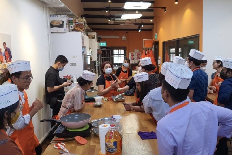 Salah satu keriuhan di kelas memasak makanan tradisional Singapura di Food Playground di Singapura pada awal Agustus 2022. Para jurnalis sedang mendengarkan instruksi dari Teresa, seorang ibu rumah tangga yang menjadi instruktur kelas memasak di Food Playground.