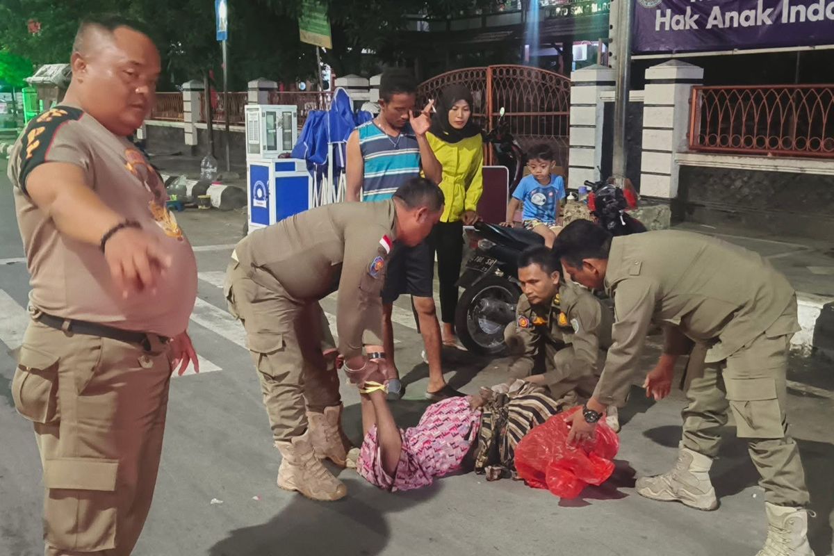 Petugas Satpol PP Indramayu saat proses pengamanan ODGJ yang mengamuk di Jalan Letjen S. Parman, tepatnya di depan SDN Margadadi 5 Indramayu, Jawa Barat, Minggu (30/11/2025) malam.