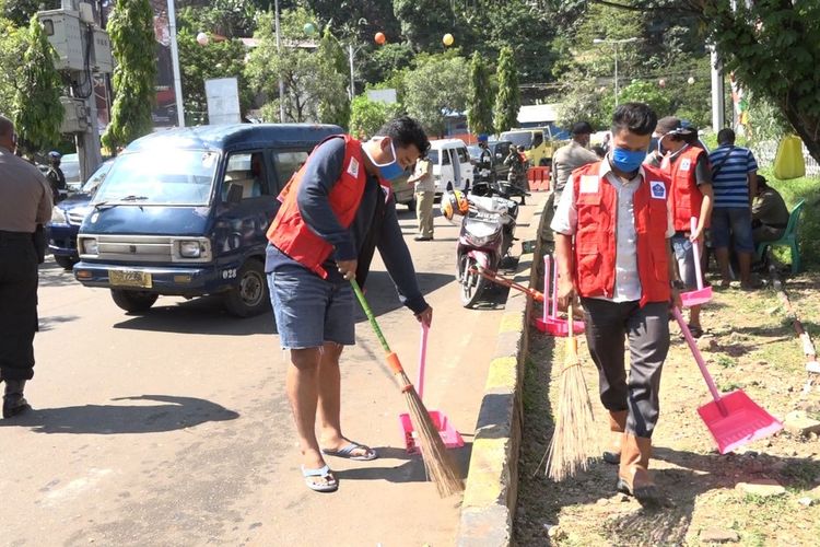 Beberapa warga Kota Jayapura yang terjaring razia masker sedang dihukum melakukan pekerjaan sosial dengan membersihkan fasilitas umum dan menggunakan rompi berlabel OKB atau orang kepala batu, Jayapura, Papua, Selasa (23/6/2020)