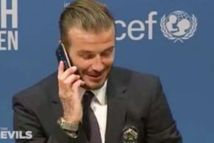 David Beckham saat mengangkat telepon milik wartawan seusai laga amal Unicef, Sabtu (14/11/2015).