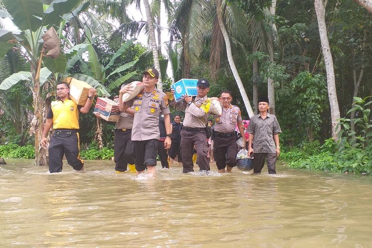 Petugas kepolisian memikul bantuan paket sembako yang akan diberikan kepada warga terdampak banjir di Desa Pulau Rambai, Kecamatan Kampa, Kabupaten Kampar, Riau, Sabtu (14/12/2019).
