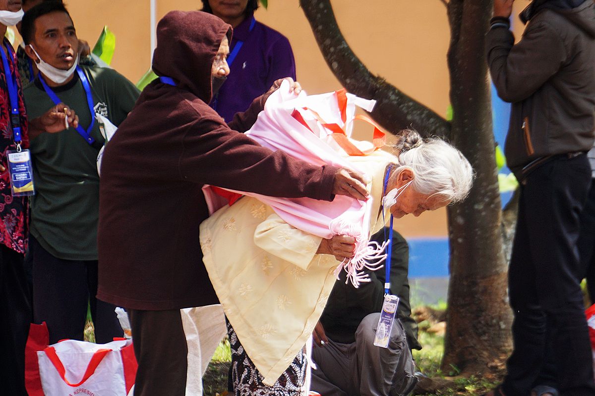 Warga membantu seorang perempuan lansia menggotong bantuan beras dan sembako dari negara yang diberikan oleh Presiden Joko Widodo saat mengecek penyaluran bantuan pangan di Gudang Bulog, Klahang, Sokaraja, Banyumas, Jawa Tengah, Rabu (3/1/2024).