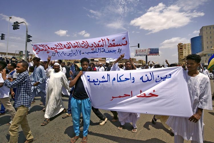 Dua orang pengunjuk rasa memegang spanduk bertuliskan dalam bahasa Arab yang artinya, Agama Allah dan hukum Syariah adalah mutlak sementara di belakangnya spanduk lain bertuliskan turunkan amendemen (konstitusi) yang bertentangan dengan Syariah Islam selama demonstrasi di sepanjang Siteen Street (60 Street) di distrik Khartoum Timur ibu kota Sudan pada Jumat 17 Juli 2020 kemarin.